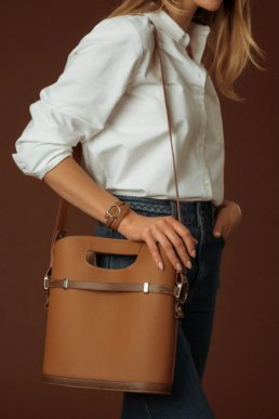 Photographie studio d'un bracelet et d'un sac en cuir marron, pour femme, porté par une mannequin.