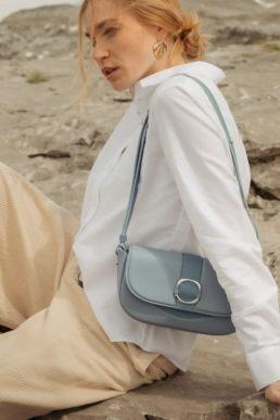 Portrait lifestyle d'une femme avec le sac en cuir bleu Ainhoa de la marque Erro lors d'un shooting photo en extérieur.